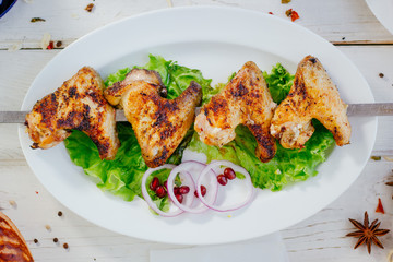Top view of grilled chicken wings on white plate.
