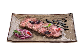 slices of roast beef appetizer with red onion and balsamic sauce on grey plate isolated on white background