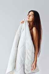 Fototapeta premium Woman covering her body by towel in the studio against white background