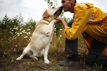 Big dog near anonymous master among green plants