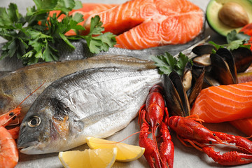Fresh fish and different seafood on light grey table, closeup
