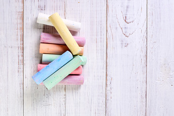Multicolored chalk for drawing on a light wooden background. The concept of children's creativity.