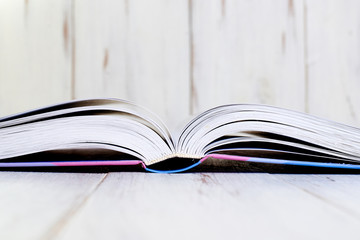 Opened book on a light wooden background.