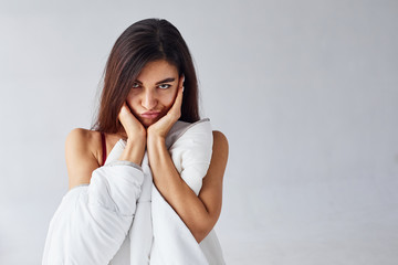 Touching face by hands. Woman covering her body by towel in the studio against white background