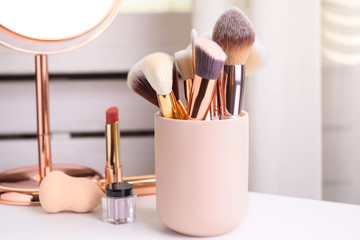 Set of professional makeup brushes in holder on dressing table