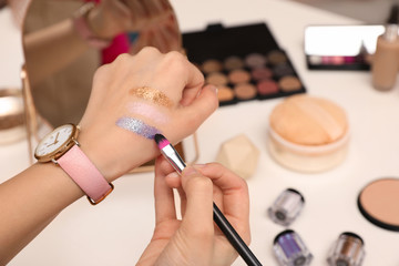 Beauty blogger doing eyeshadow swatches at table, closeup
