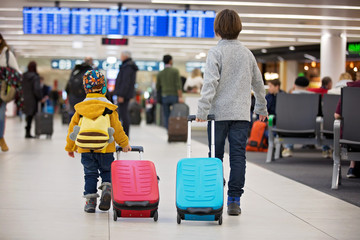 Blonde toddler boy with family, traveling with airplane, running at the airport