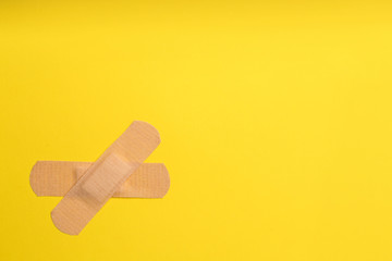 Sticking plasters on yellow background, top view. Space for text