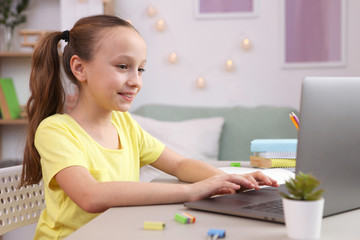 Cute little girl is doing homework in the interior of the room.