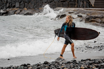 Surfer with a board in hands on the beach