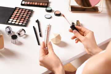 Beauty blogger with liquid eyeshadow at table, closeup