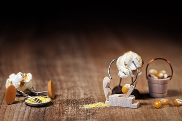 funny popcorn figure is grinding or slicing a raw corn to produce polenta or cornmeal or flour