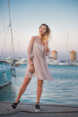 Happy glamorous beautiful girl with curly hair and an evening light dress.