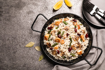 Delicious rice pilaf with chicken and vegetables on grey table, flat lay