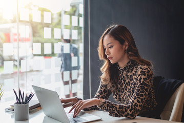 Young asian businesswoman sitting on her workplace in the office. Young woman working at laptop in...