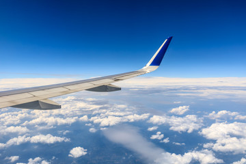 Airplane wing and beautiful blue sky with white clouds