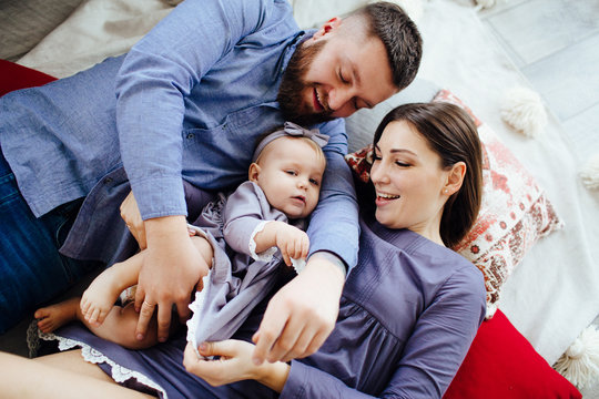 Family In Blue Clothes Happily Play With A Child On The Floor.