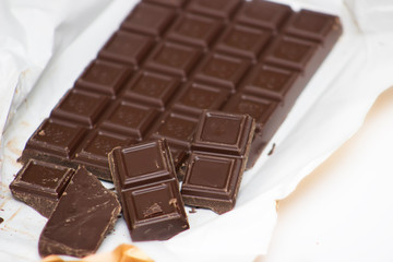 Dark chocolate in an open package on a close-up on a white background. Free space for text