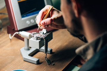 Selective focus of clockmaker working with wristwatch and watch tester at table