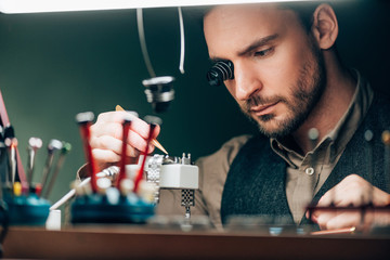 Selective focus of watchmaker repairing wristwatch at table