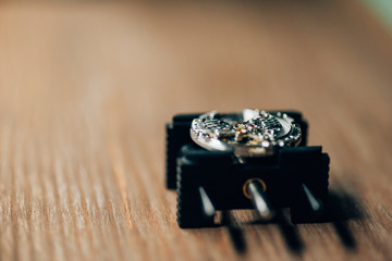 Selective focus of movement holder with wristwatch on wooden table