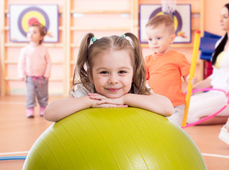 Smiling pretty child with fitness ball in gym. Gym class for preschool kids in kindergarten