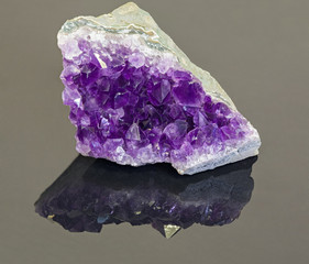 lilac amethyst in geode on grey background