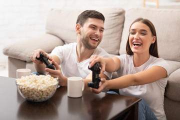 Joyful Couple Playing Video Game Sitting On Sofa At Home