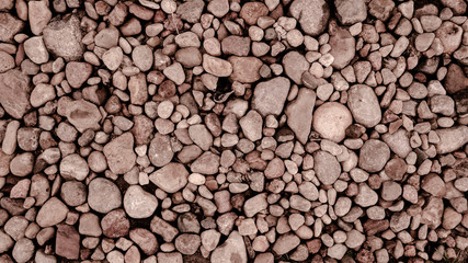 Red and brown stones on the sea coast. Pebbles lying on the beach.Wall of small stones.