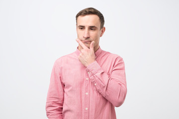 Pensive caucasian young man thinking or considering idea, looking at free copy space aside.