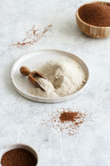 Obraz na płótnie Canvas Teff flour on a plate with a spoon and teff grain