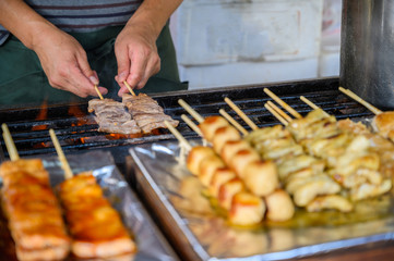 Traditional some meat skewers being grilled in a barbecue, in Japan at street food vendor market, grilled satay. Japanese Food.