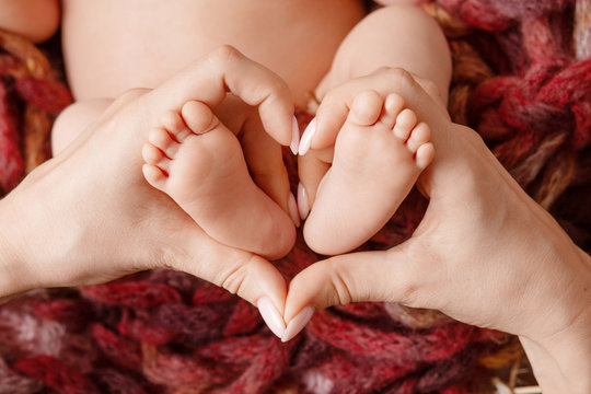Baby feet in mother hands - hearth shape closeup. Mom and her Child. Happy Family concept. Beautiful conceptual image of Maternity.