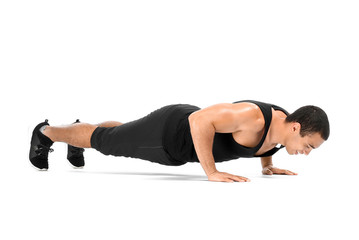 Fototapeta premium Sporty African-American man doing push-ups on white background