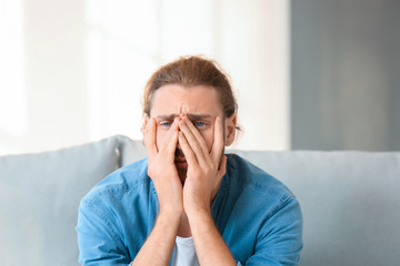Depressed man sitting on sofa at home
