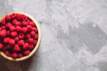 raspberries in wood bowl on gray table, vintage