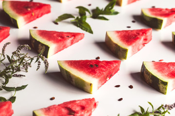 sliced triangular slices of ripe red watermelon with seeds with green mint leaves, lime
