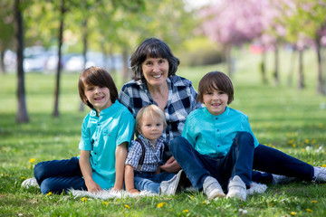 Fototapeta premium Grandmother and children in a beautiful blooming spring park