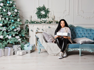 Fototapeta premium Happy brunette women in Christmas decorations with gift box.