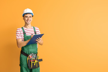 Handsome male worker with clipboard on color background