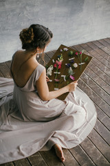 A girl in a Pink Dress Looks at Fresh Flowers on a Board