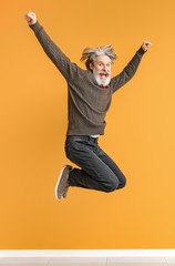 Jumping elderly man on color background