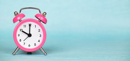 Save time, daylight saving concept, pink alarm clock on a blue background, web banner with copy space