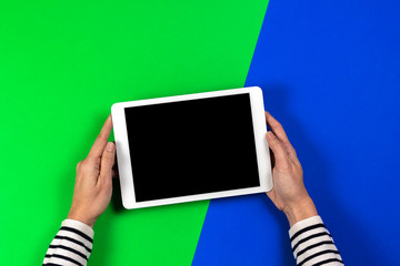 Woman hands holding digital tablet computer on green and blue background