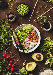 Healthy lunch, dinner. Flat-lay of salmon poke bowl or sushi bowl with various vegetables, greens,...