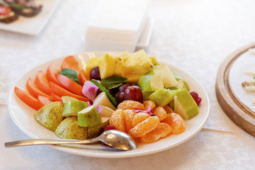 A plate of fresh fruit on the dinner table. Useful and delicious food. Fresh vitamins in natural composition.
