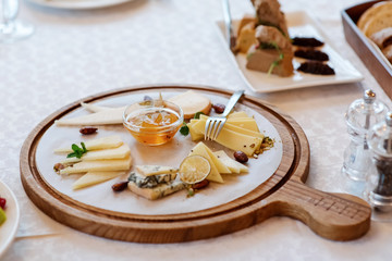 Confiture and cheese cut on a wooden board. Assortment of cut slices of different cheese varieties.
