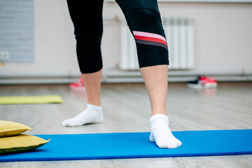 Zumba. Fitness training of one woman. Legs on the mat. Yoga mat. The basic movement of the zumba. Legs of a girl in white socks during training.