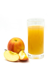 naturally cloudy apple juice - sliced yellow, ​red apples with a glass of naturally cloudy apple juice in front of white background