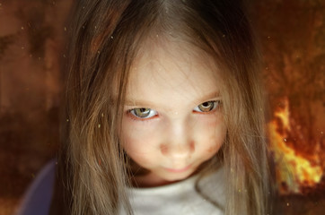  little girl child with an evil gaze tripled the fire. frame from a horror movie